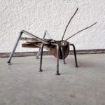 Ručně vyráběná kovová socha kobylky s tělem z hasáku, očima z uzavřených matic a nohama z hřebíků a šroubů. Povrchová úprava bezbarvým lakem pro komaxitové nátěry.